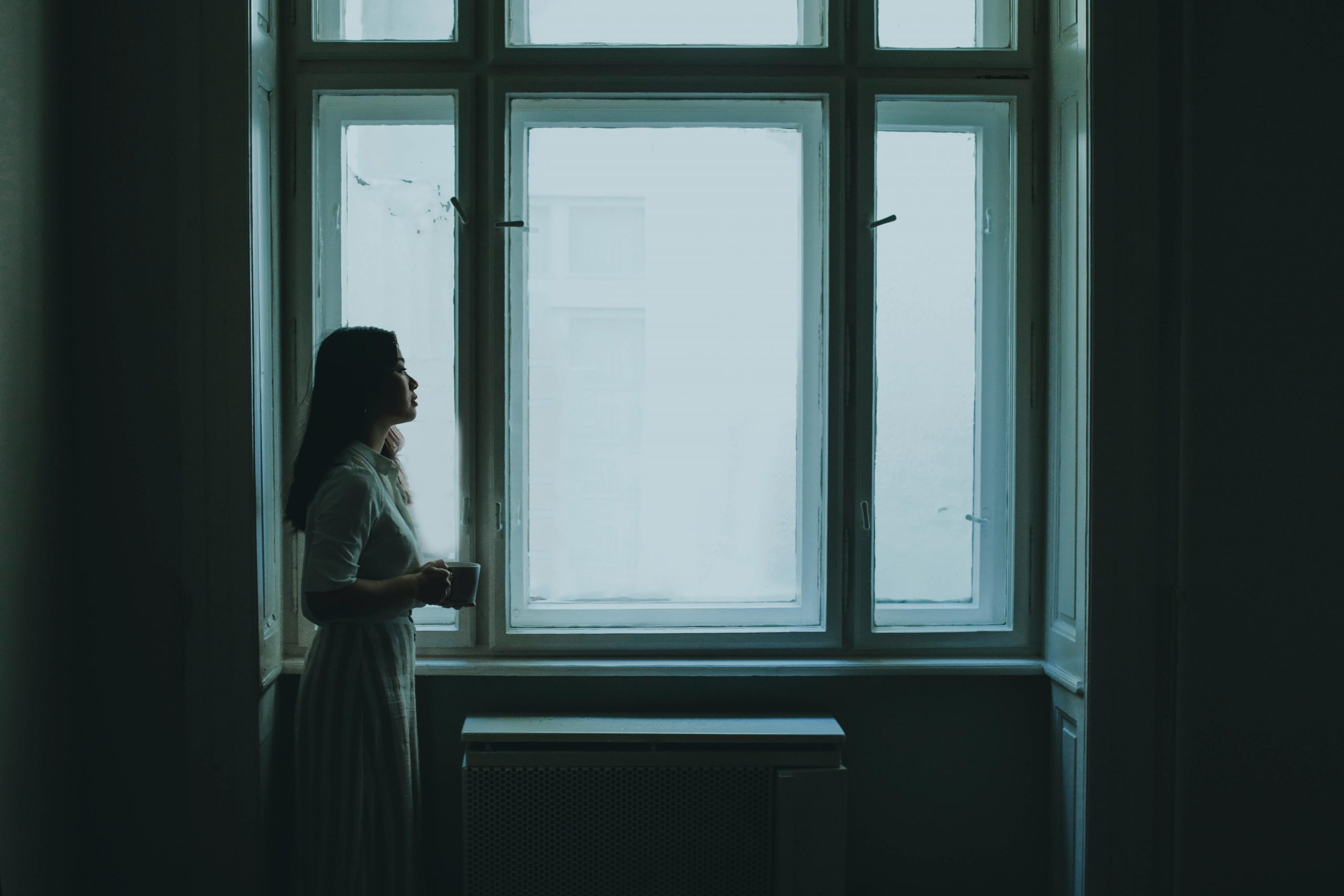 woman looking out a window on a gloomy day